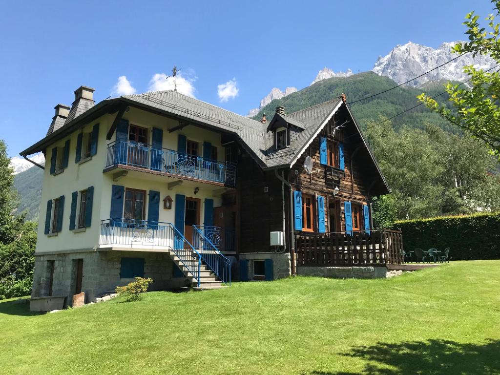 una casa grande en un campo de hierba con una montaña en La Crèmerie du Vernet en Chamonix-Mont-Blanc
