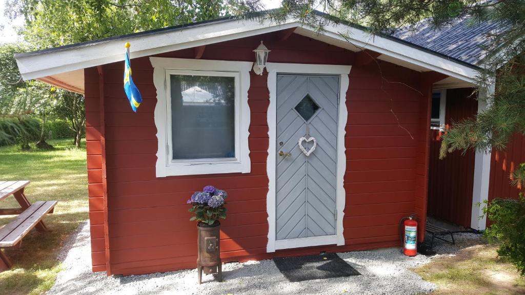 einem roten Schuppen mit Tür und Fenster in der Unterkunft Sollyan in Knivsta