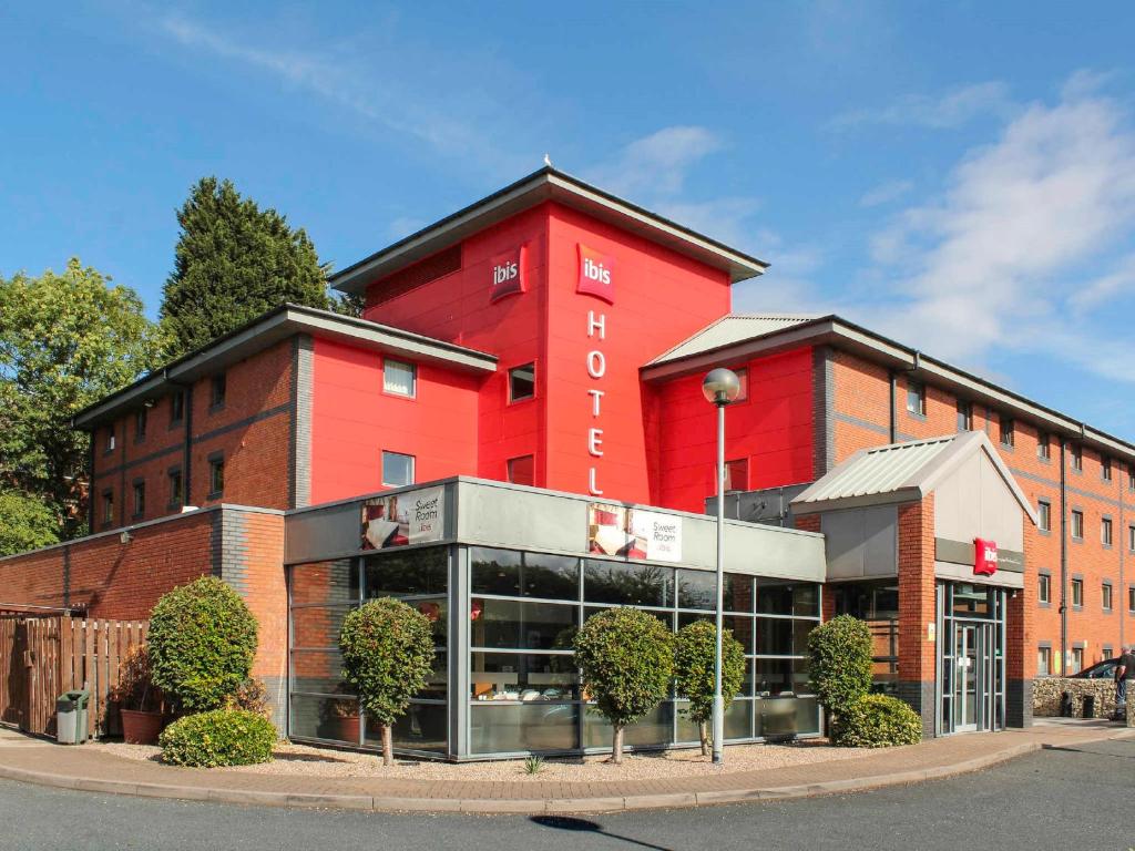 um edifício vermelho com uma loja em frente em ibis Birmingham Bordesley em Birmingham