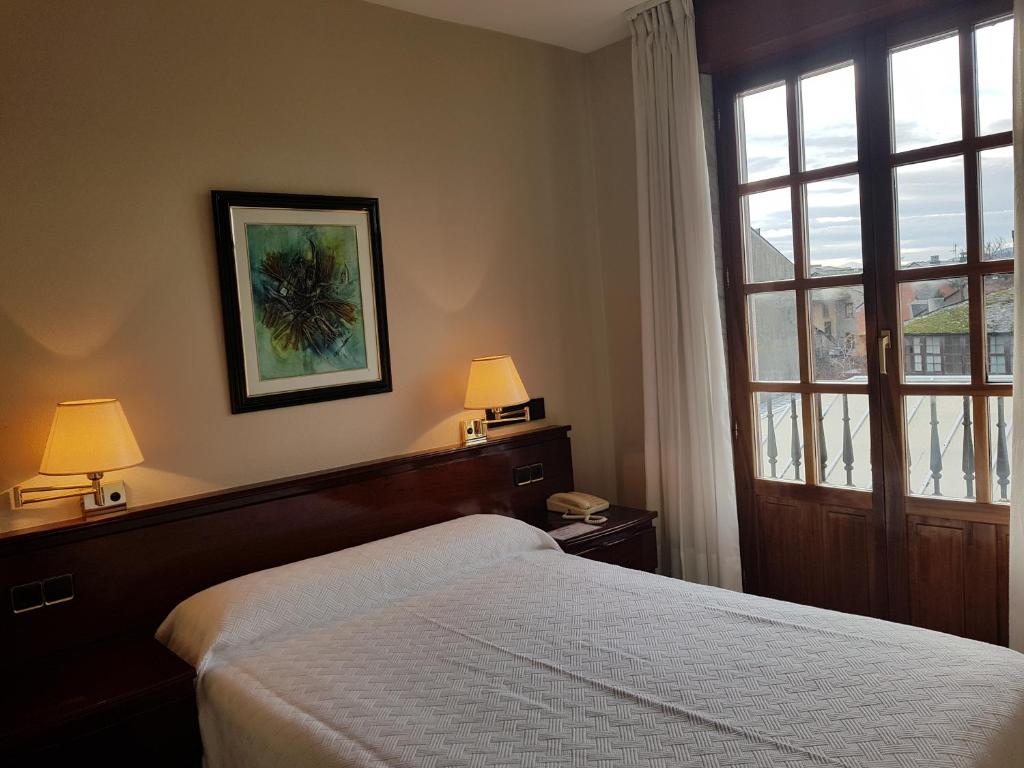 um quarto com uma cama, uma janela e 2 candeeiros em Hostal Santa Maria em Cacabelos