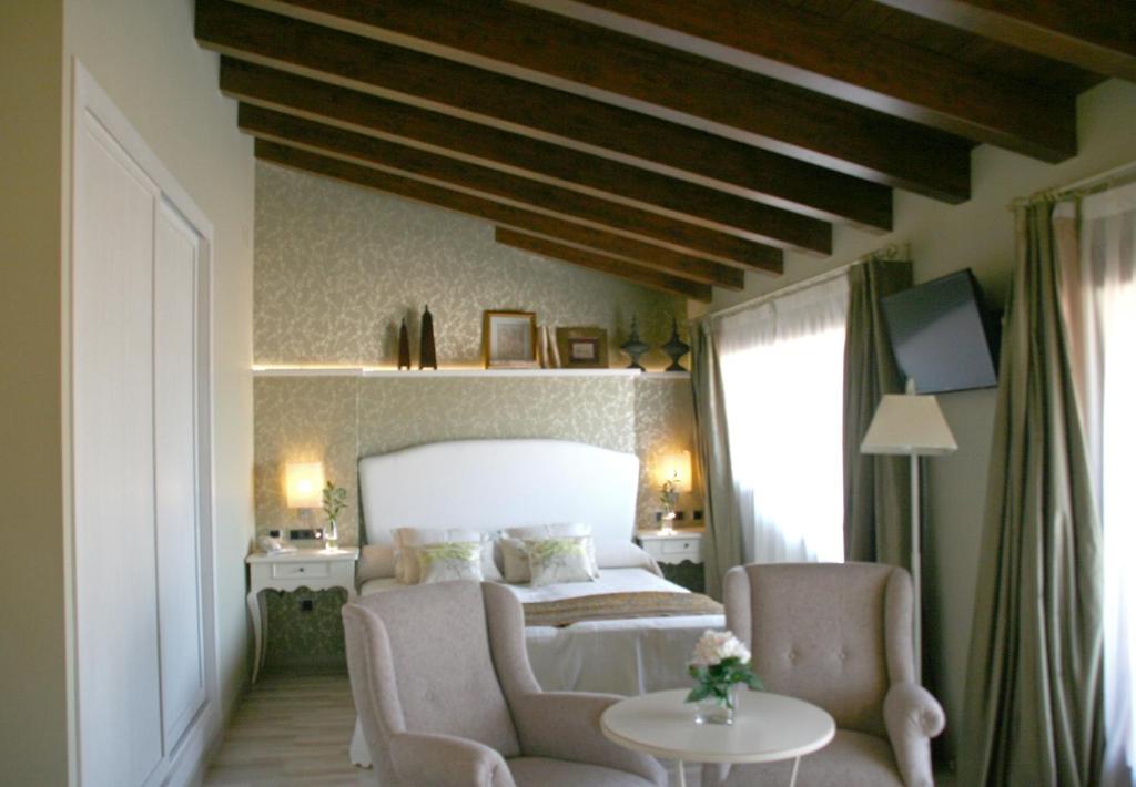 a bedroom with a bed and two chairs and a table at Hotel Castillo in Alquézar