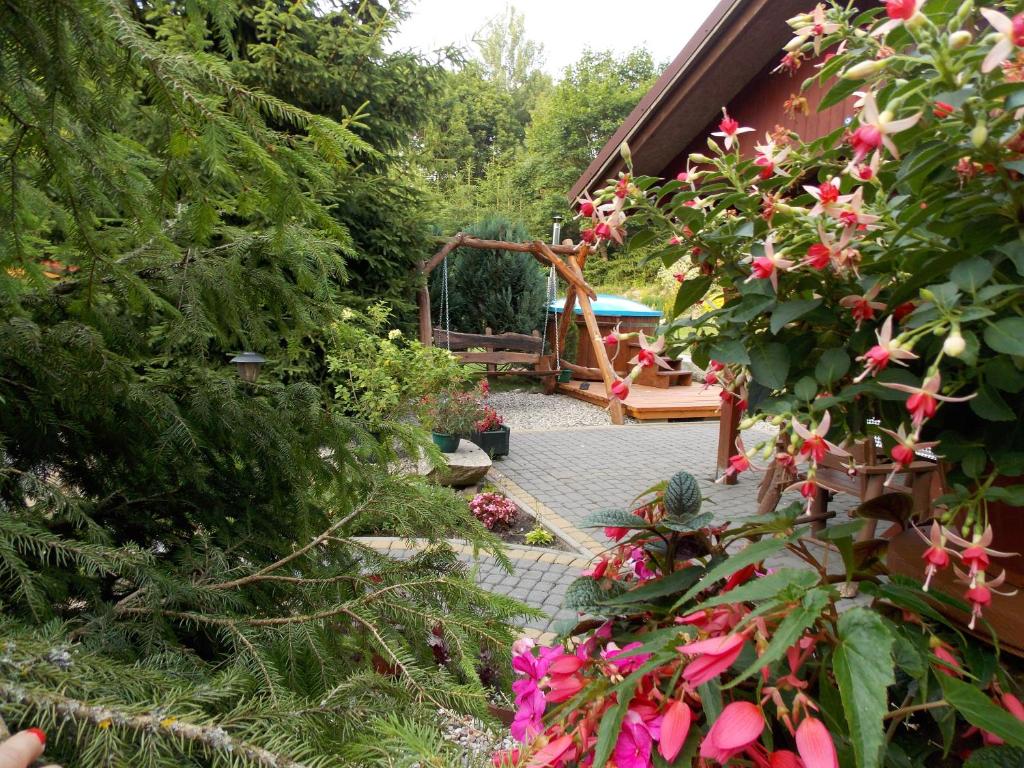 a garden with pink flowers and a playground in the background at Domek pod Lasem na Mazurach in Ryn