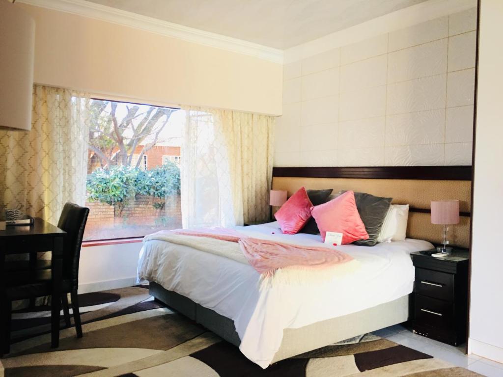 a bedroom with a bed and a window and a desk at Riverton Manor in Centurion