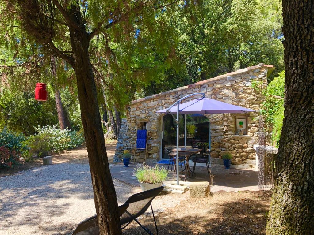 a table and an umbrella in front of a stone building at Cabanon Sainte Victoire in Saint-Marc-Jaumegarde