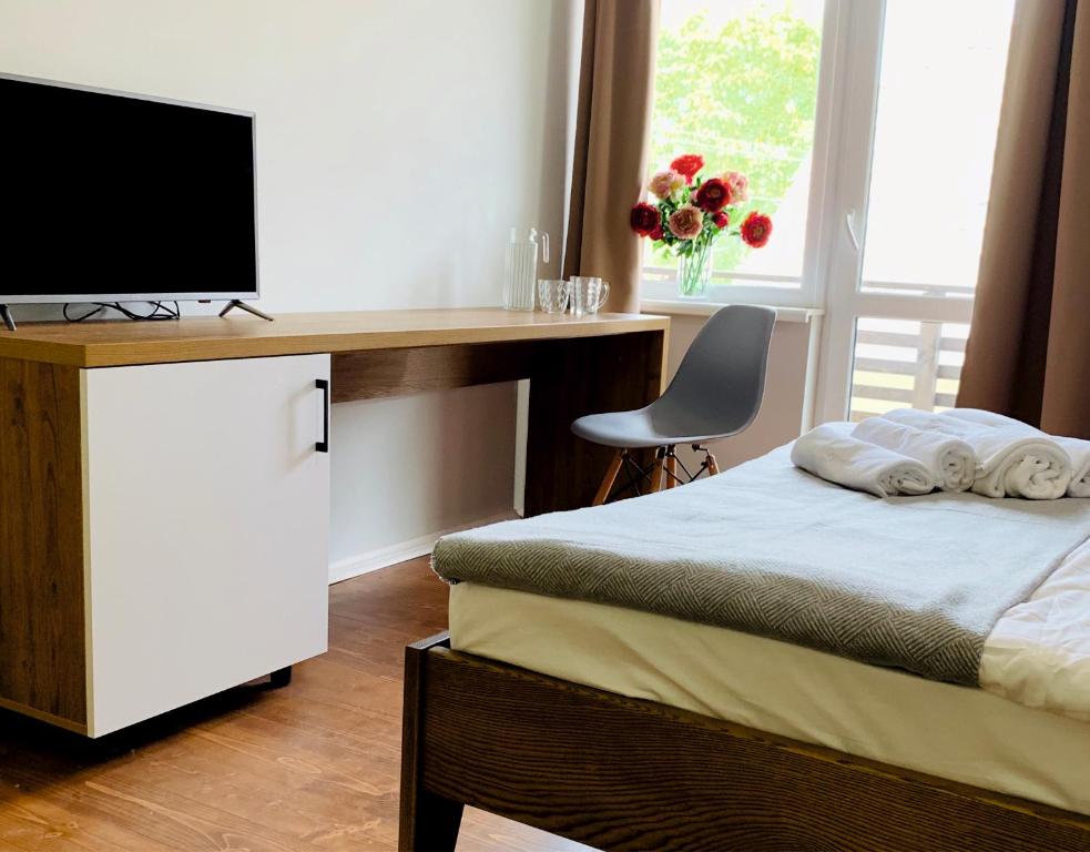 Schlafzimmer mit einem Bett und einem Schreibtisch mit einem TV in der Unterkunft Водограй, курортна вілла in Morschyn