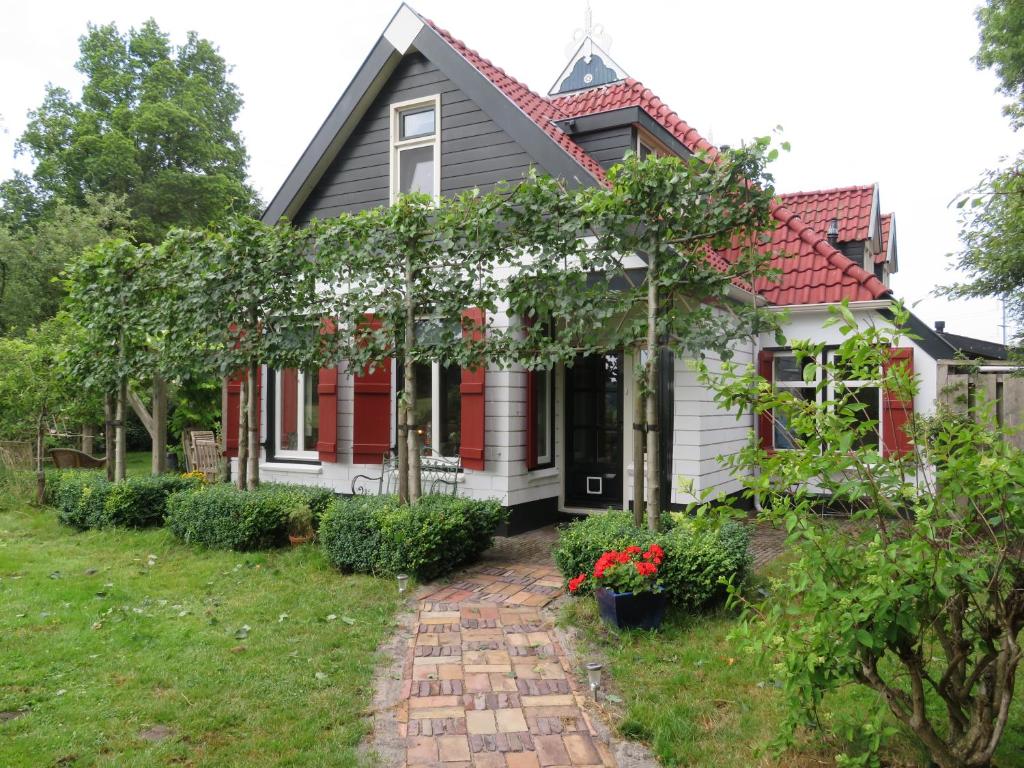 a house with a red roof and a brick pathway at B&B Singelstate in Gorredijk