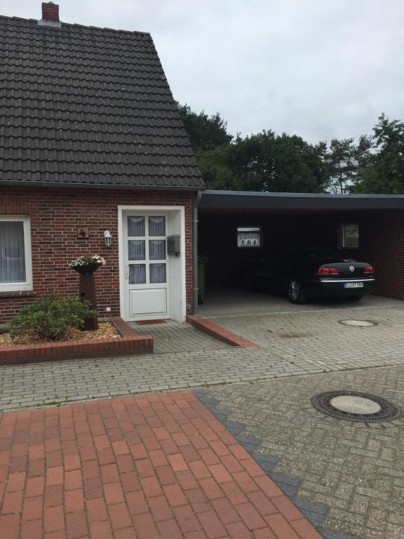 a house with a car parked in front of a garage at Gästehaus Atrico Haus 4 in Neubörger