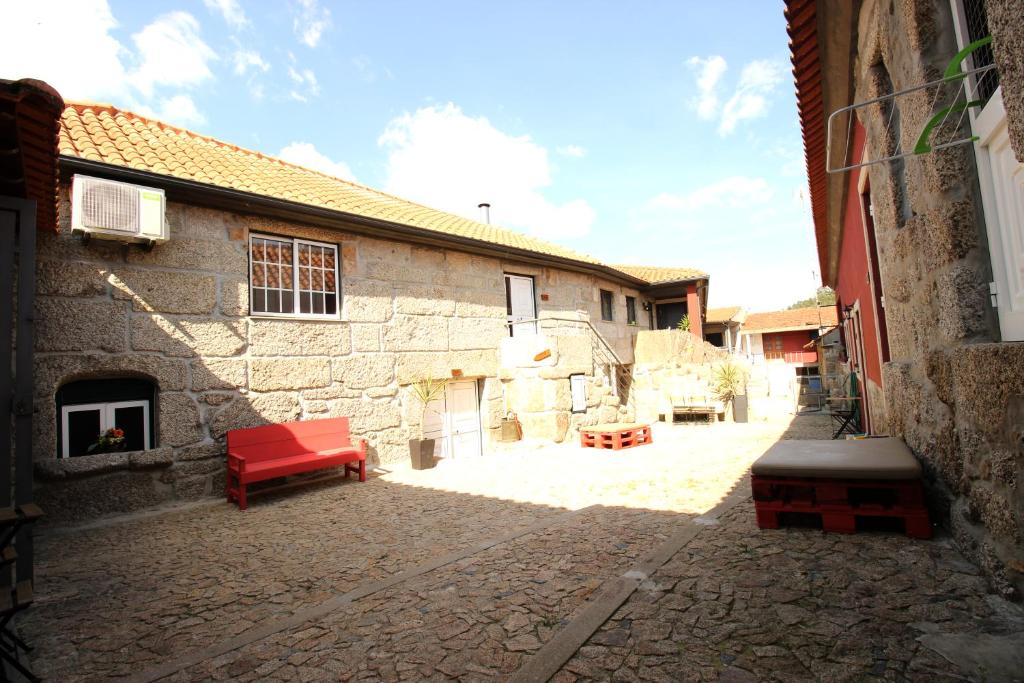 un bâtiment en briques avec un banc rouge dans une cour dans l'établissement Quinta d'Areda Wine&Pool Experience, à Fafe