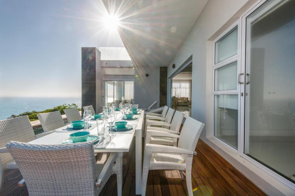 uma sala de jantar com uma mesa branca e cadeiras em Leisure and Golf Retreat Villa Pinnacle Point em Mossel Bay