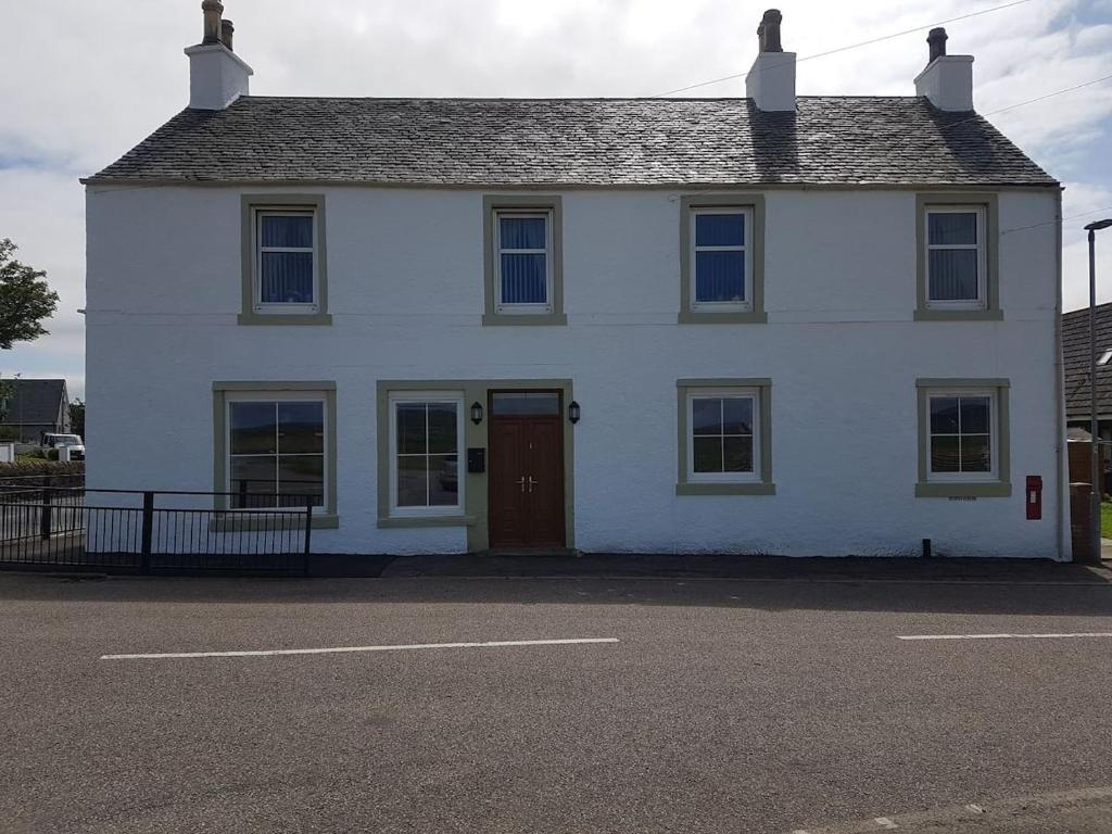 a white house with a red door on a street at Modern 1 bed Apartment close to Campbeltown in Campbeltown