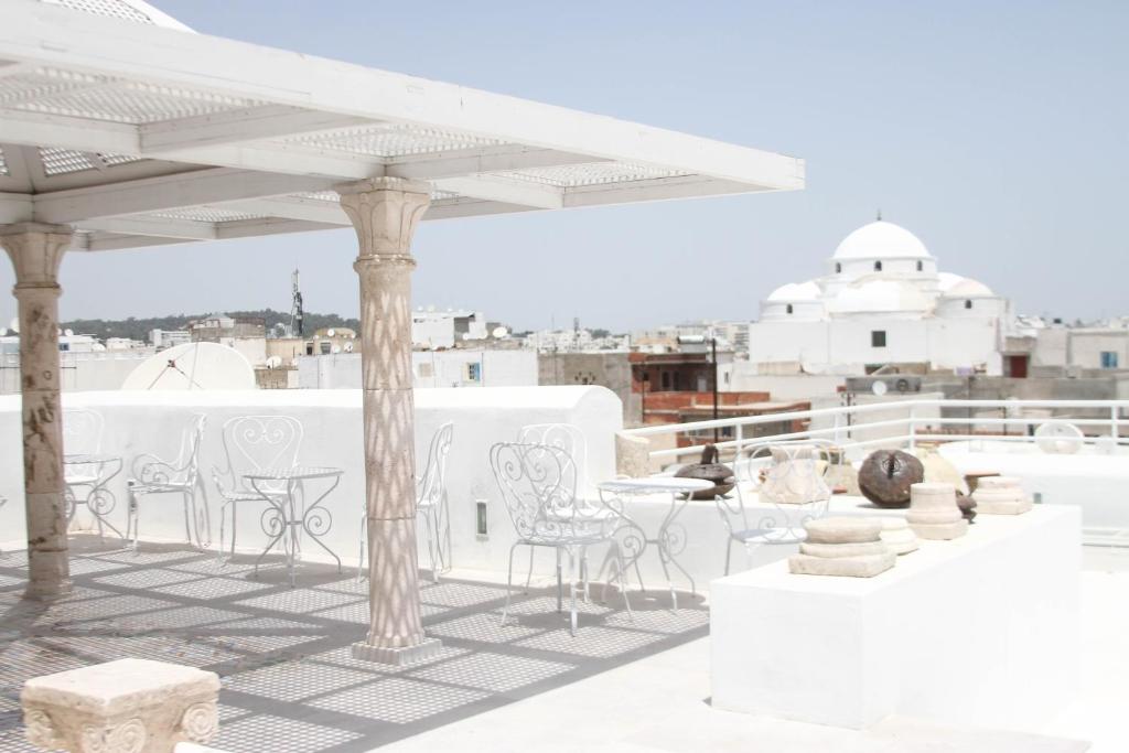 a patio with white chairs and tables on a roof at Dar Ben Gacem Kahia in Tunis