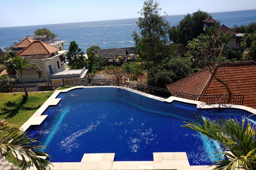 a large blue swimming pool in front of a house at Bamboo Bali Hill Bungalows in Amed