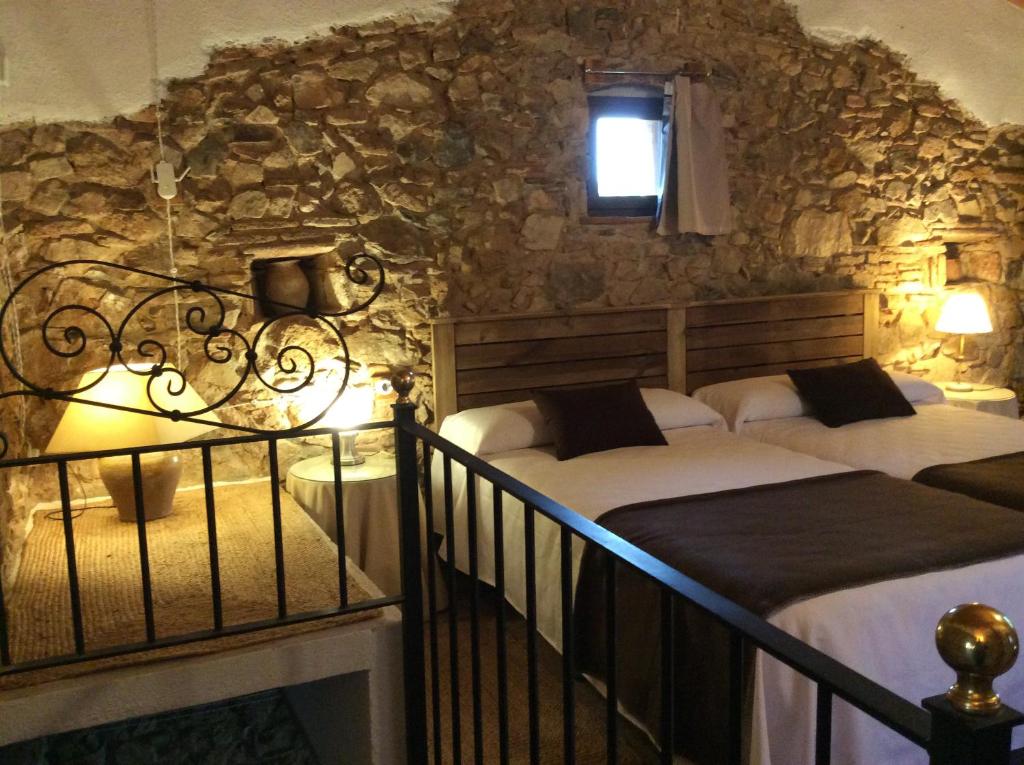 - 2 lits dans une chambre avec un mur en pierre dans l'établissement La Caseta Vella, à Falset