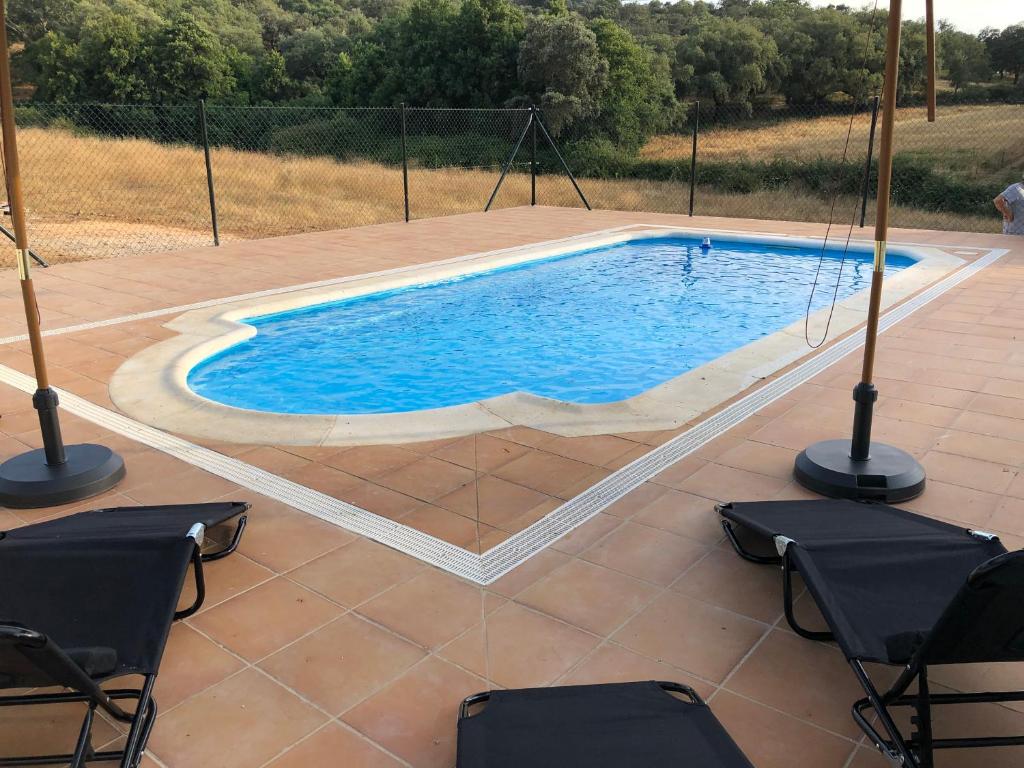 una piscina en un patio con sillas alrededor en Cercado Forero en Cortegana