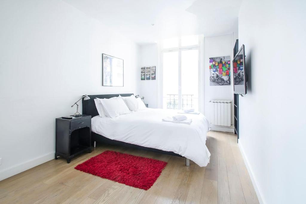 a white bedroom with a large bed with a red rug at Gorgeous Paris Eiffel Tower in Paris
