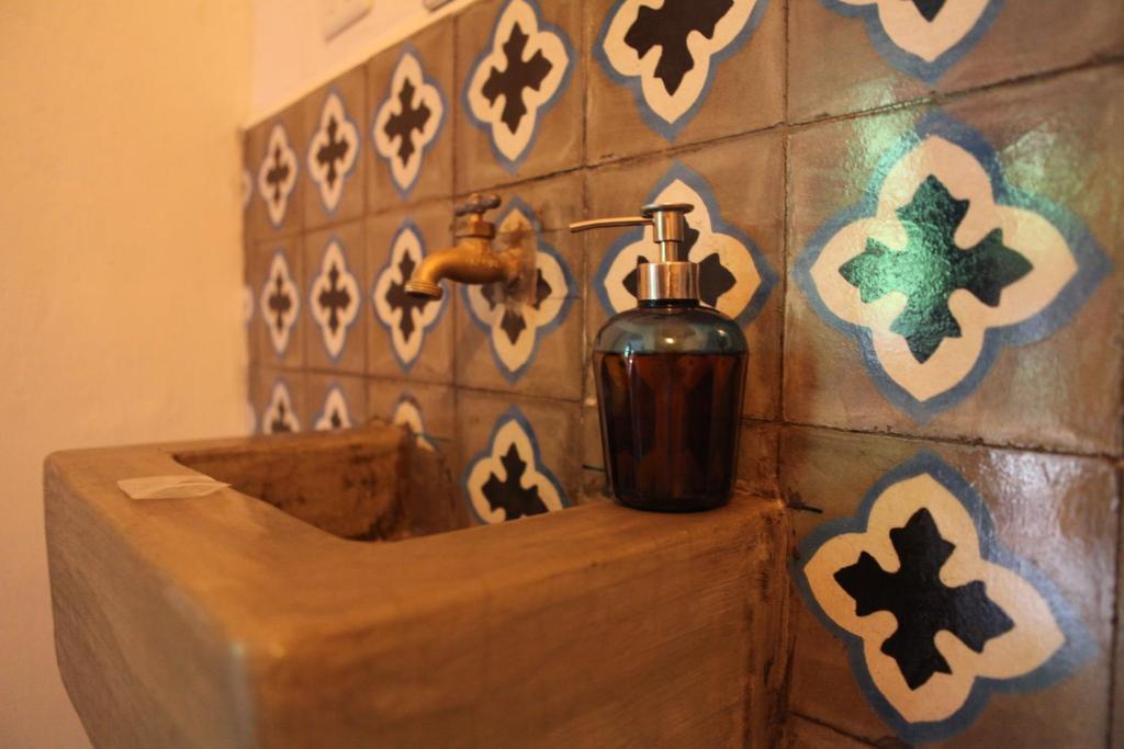 a bathroom with a soap dispenser on a tiled wall at Hostal La Tortuga Booluda in León