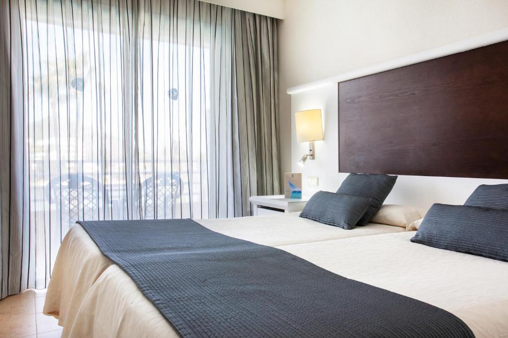 a hotel room with a bed and a large window at Grupotel Amapola in Playa de Muro