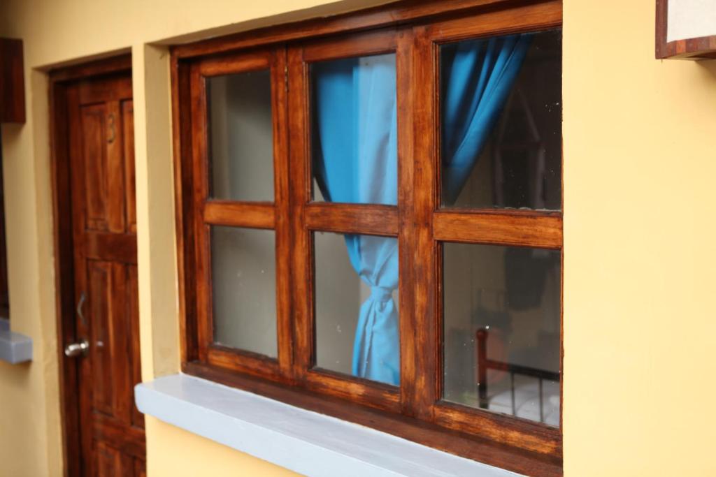 a wooden window with blue curtains in a room at Hostal La Tortuga Booluda in León