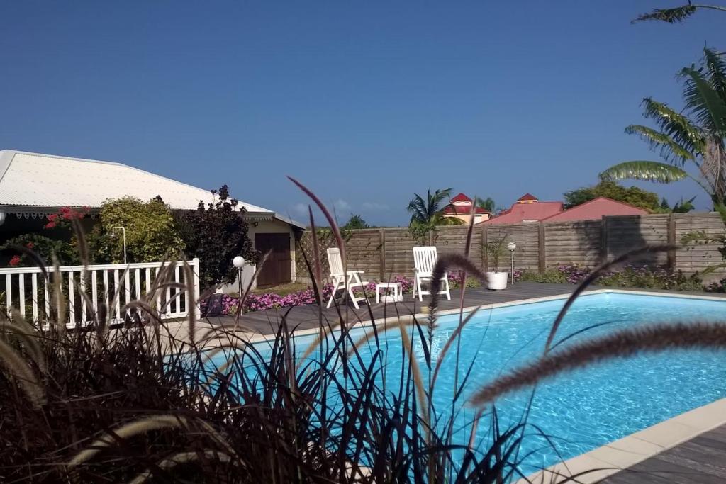 - une piscine avec 2 chaises et une clôture dans l'établissement BUNGALOW DU VOYAGEUR, au Marin