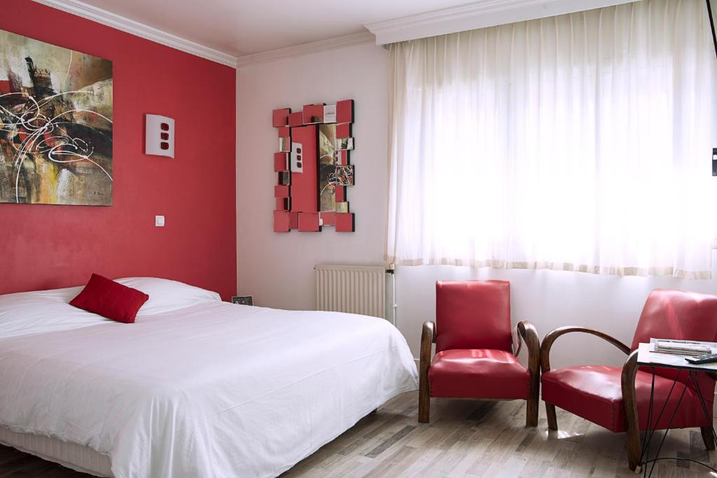 a bedroom with red walls and a bed and two chairs at Cit&#39;Hotel Europeen in Angoulême