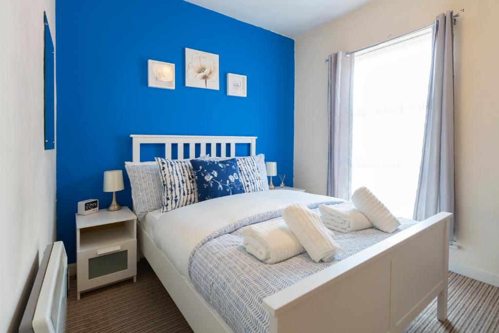a bedroom with blue walls and a bed with pillows at The Point Apartment, Leeds City Center in Leeds