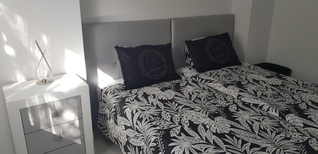 a bed with a black and white blanket and pillows at Bubu Beach 2-B in Los Cristianos