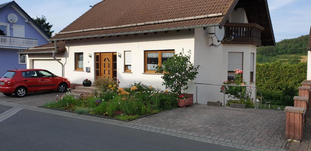 un coche rojo estacionado frente a una casa blanca en Haus Anna, en Kelberg