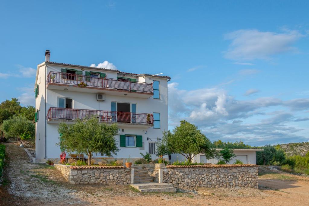 een wit gebouw met bomen ervoor bij Apartmani Lana in Skradin