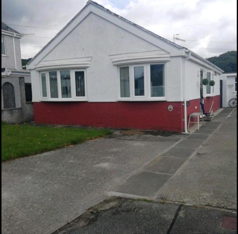 a red and white house with a red and white at Private bedroom in a detached bungalow in Porthmadog
