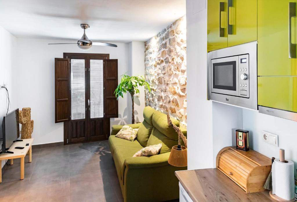 Una sala de estar con un sofá verde y un televisor. en Alojamiento San Nicolas, en Úbeda