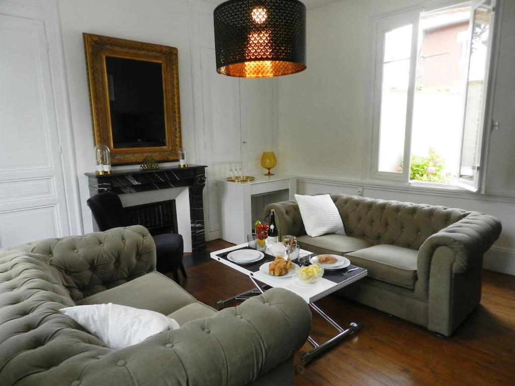 ein Wohnzimmer mit 2 Sofas und einem Tisch in der Unterkunft Chez Paulette in Pont-Audemer