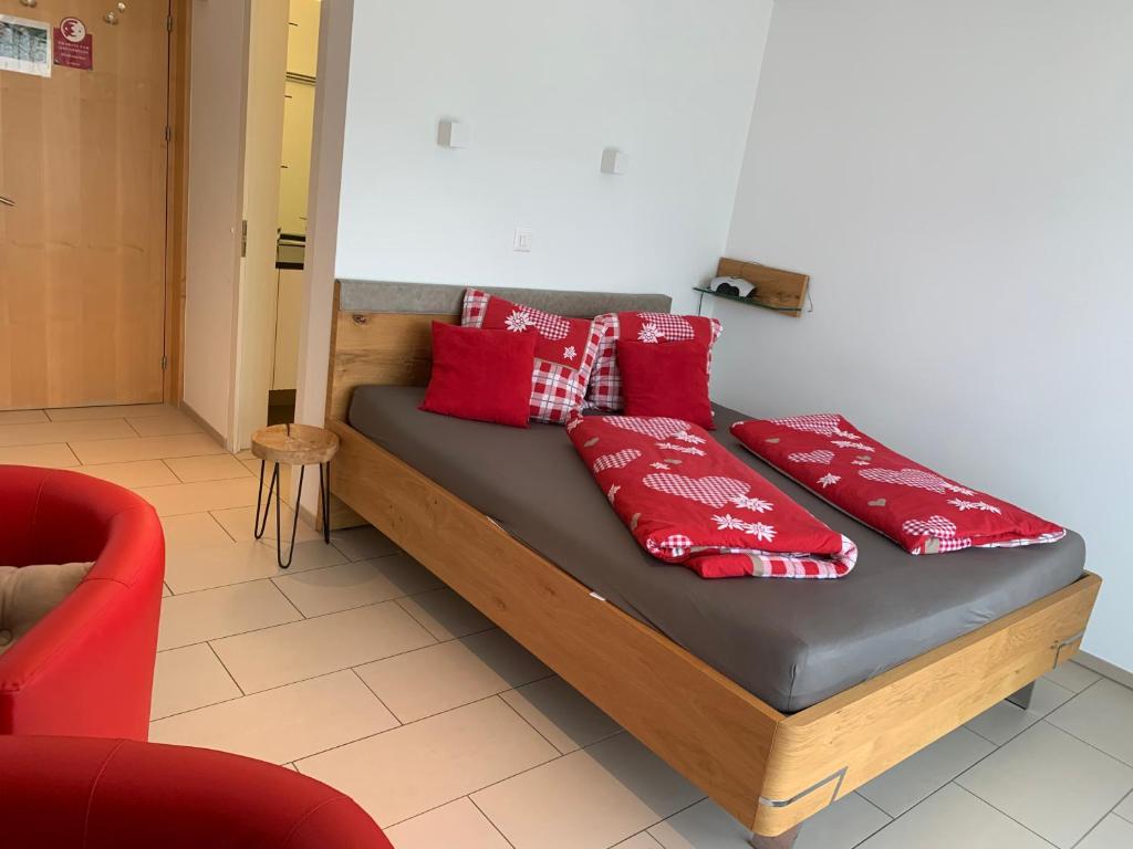 Bett mit roten Kissen auf einem Zimmer in der Unterkunft Ustria / Pensiun Trutg in Vella