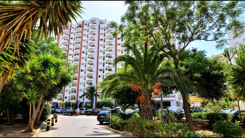 ein Gebäude mit Palmen vor einer Straße in der Unterkunft Praia da Rocha Apartment 3 in Portimão