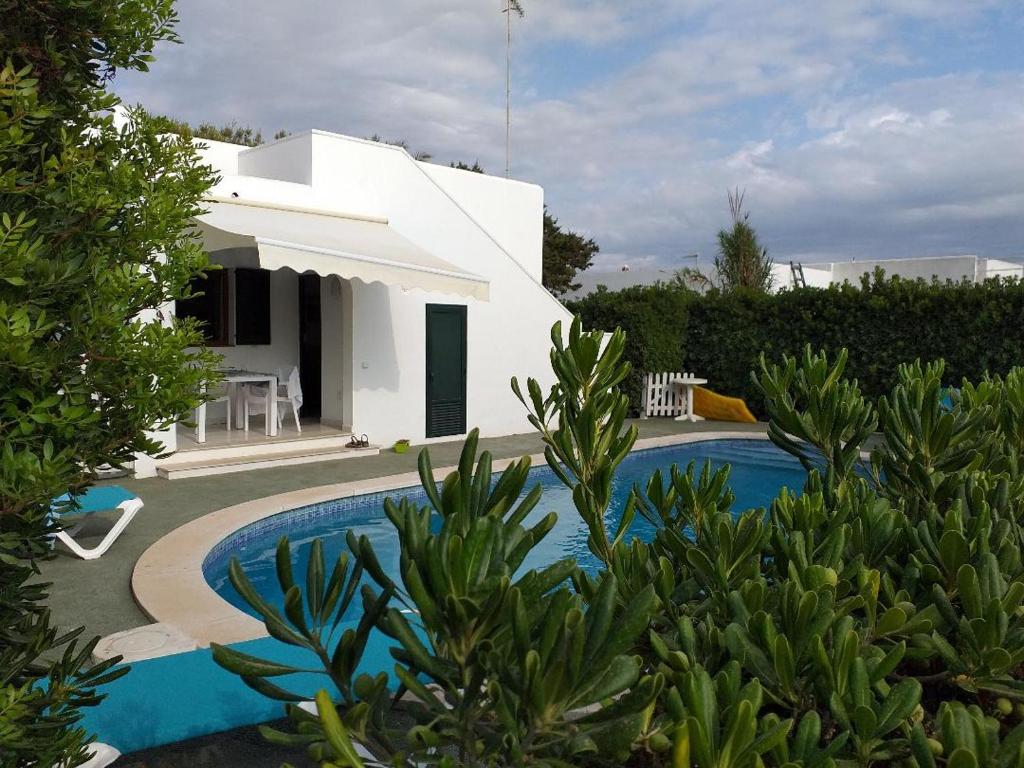 une villa avec une piscine en face d'une maison dans l'établissement Apartamentos Delfines, à Cala Blanca