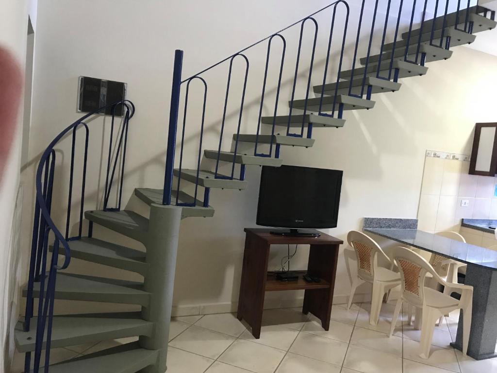 a living room with a staircase with a tv and a table at Chalés Multicores in Ubatuba