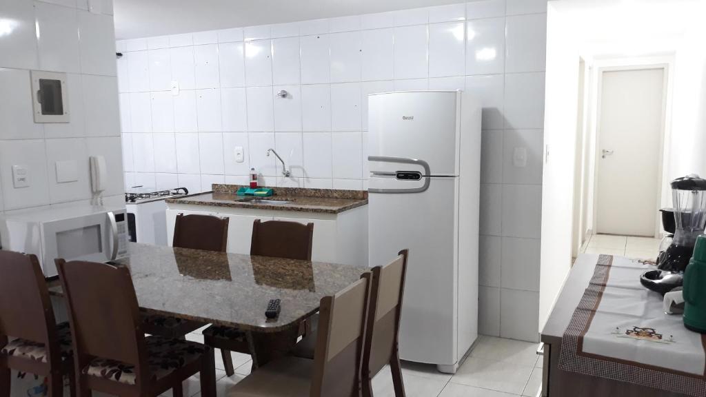 eine Küche mit einem Tisch und einem weißen Kühlschrank in der Unterkunft Marcella's Holiday House - 100 mts Praia do Morro in Guarapari