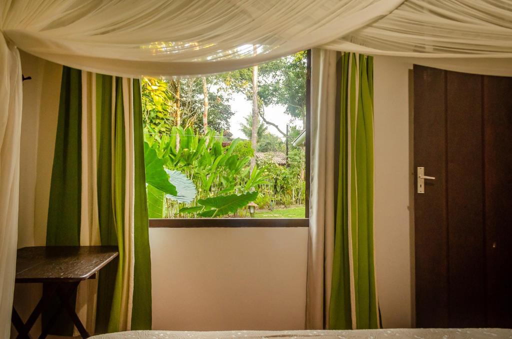 a bedroom with a window with green and white curtains at Espaço Pégasus in Trancoso