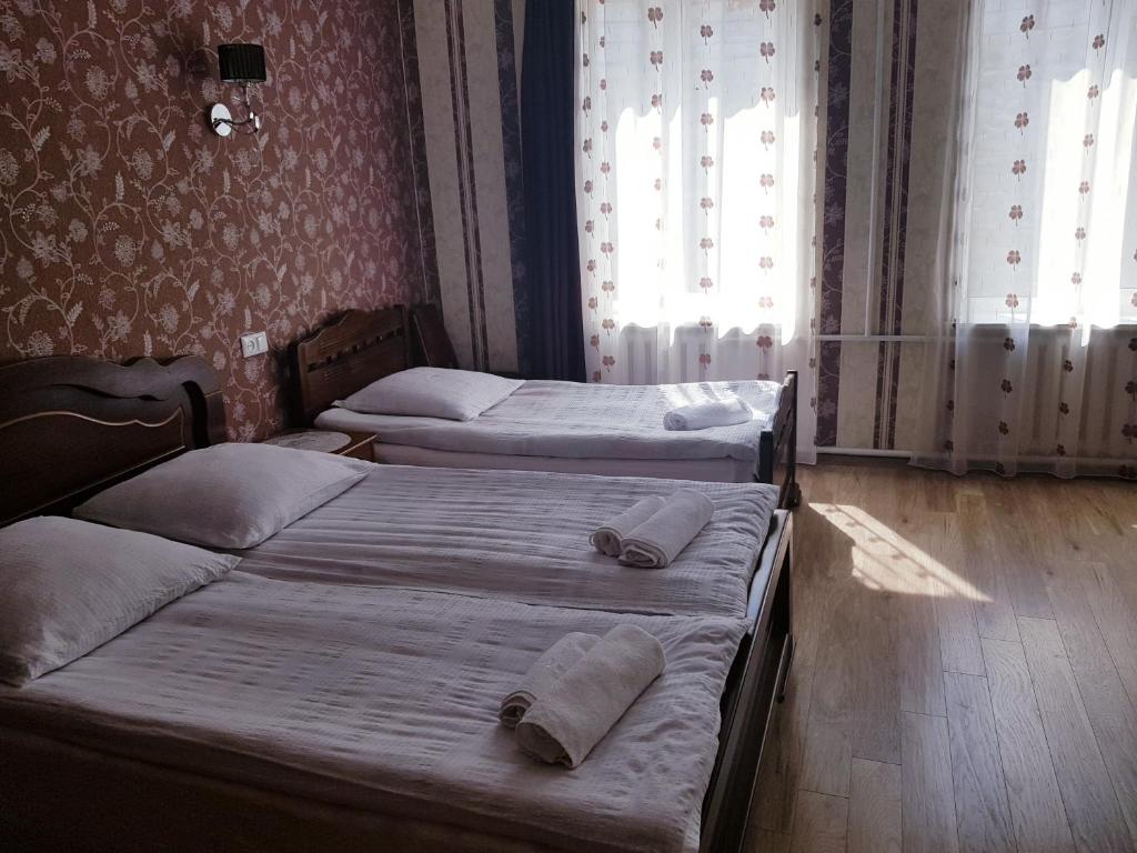 two twin beds in a room with two windows at Lia&Ramaz Guest House in Kazbegi