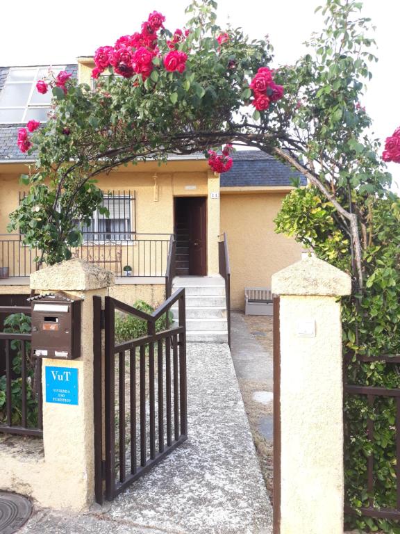 een huis met een hek met rozen erop bij Casa Rural Alameda con chimenea y jardín in El Barco de Ávila