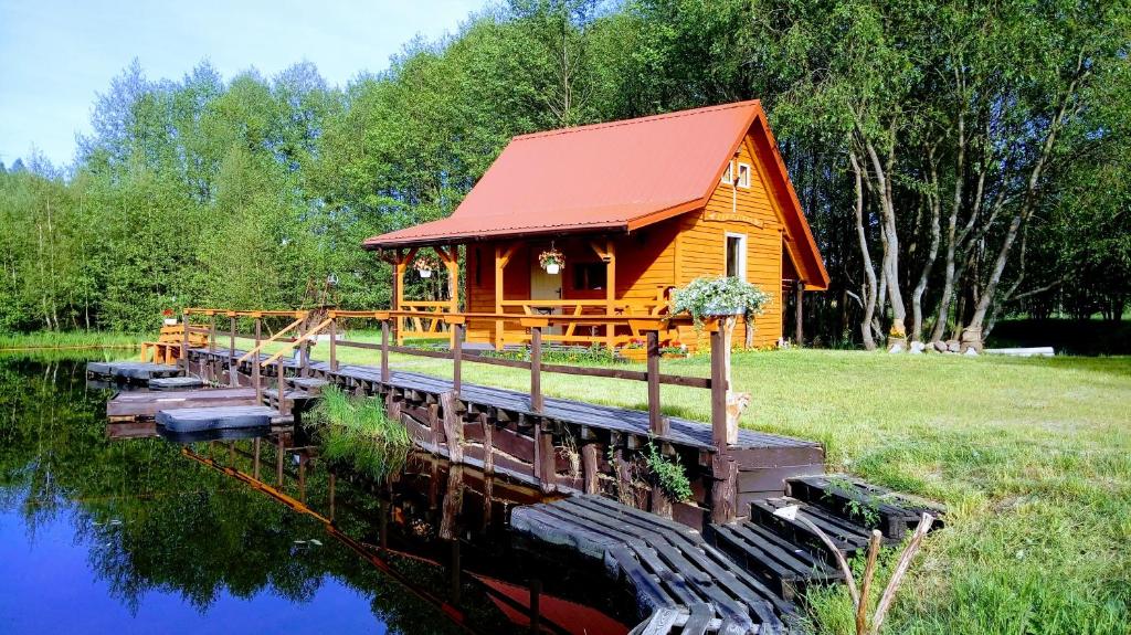 a cabin on the water with a red roof at Domek Łukaszówka in Jonkowo