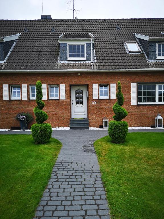 a brick house with a white door and two bushes at Casa Mediterrana in Erkrath