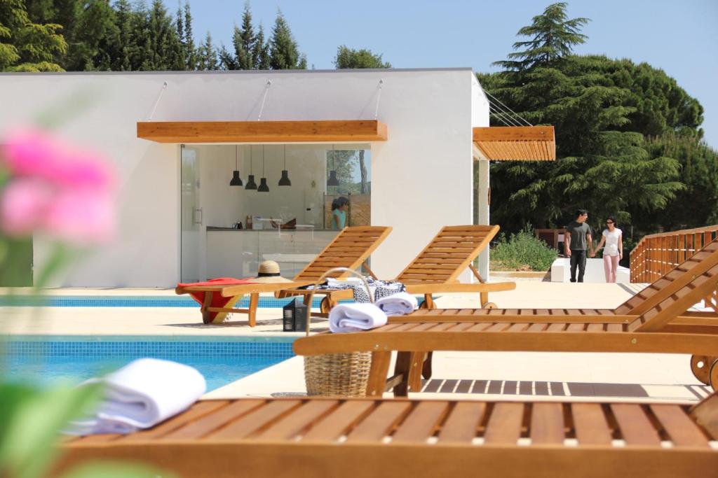 una piscina con tumbonas de madera y una casa en Casas Do Rio Sado - Sado River Country Retreat en Santa Margarida do Sado