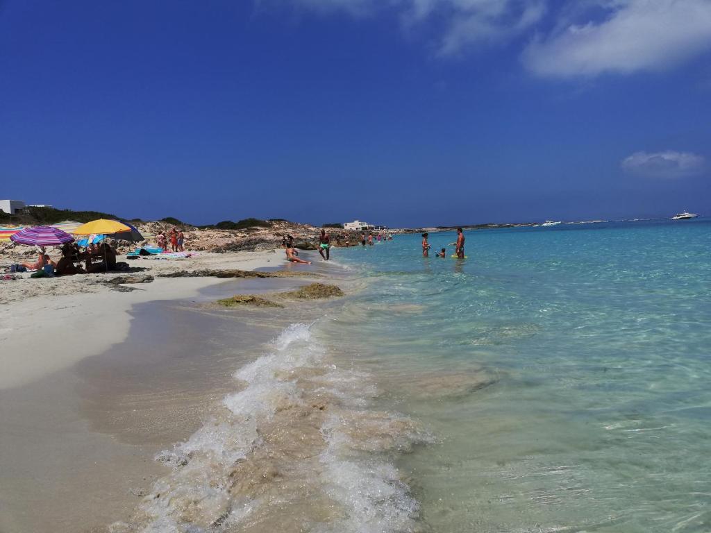 a beach with a group of people in the water at Apartamentos Las Dunas de Levante in Es Pujols