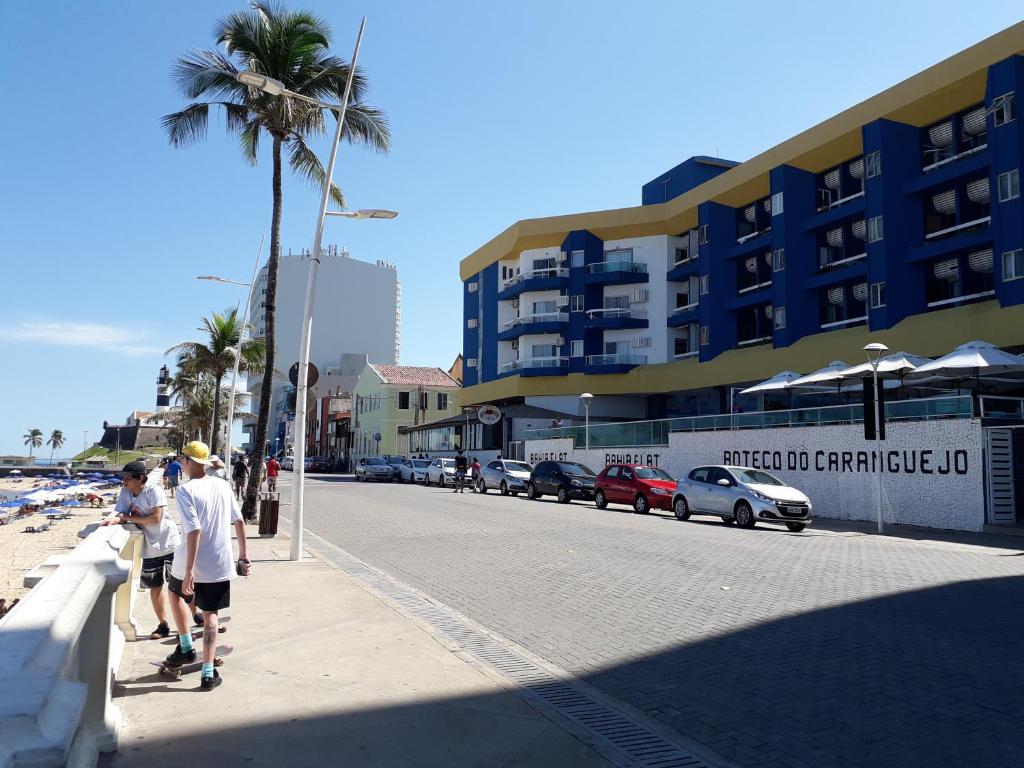 un grupo de personas caminando por una acera al lado de un edificio en Bahia Flat, en Salvador