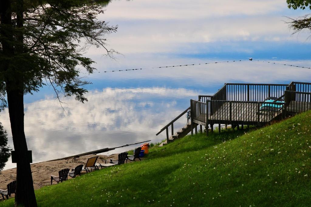 grupa ławek siedzących na wzgórzu z widokiem na wodę w obiekcie Sunny Point Resort Ltd. w mieście Otter Lake