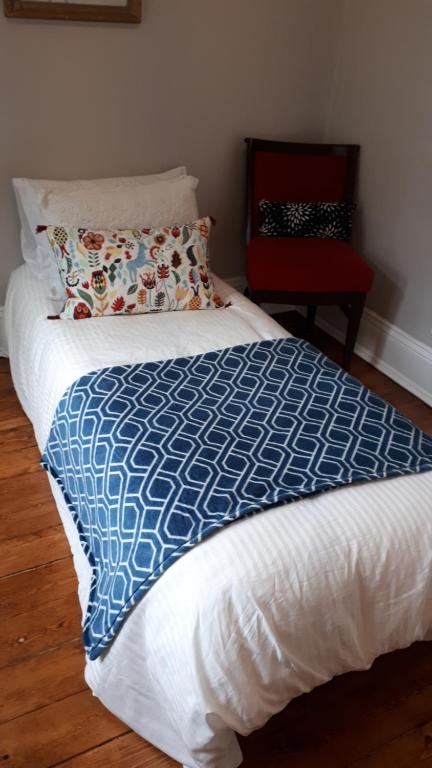 a bed with a blue and white blanket and a red chair at Hillside Landing B&B in Digby