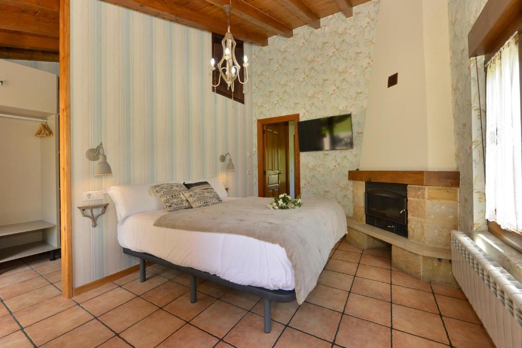 1 dormitorio con cama, chimenea y lámpara de araña en Piscina en Casa Rural con Encanto El Puentuco una de las casas mas valoradas de Cantabria en Villacarriedo