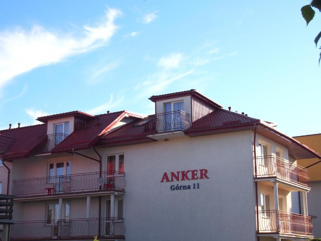 a building with a sign on the side of it at Pensjonat Anker pokoje in Ustronie Morskie