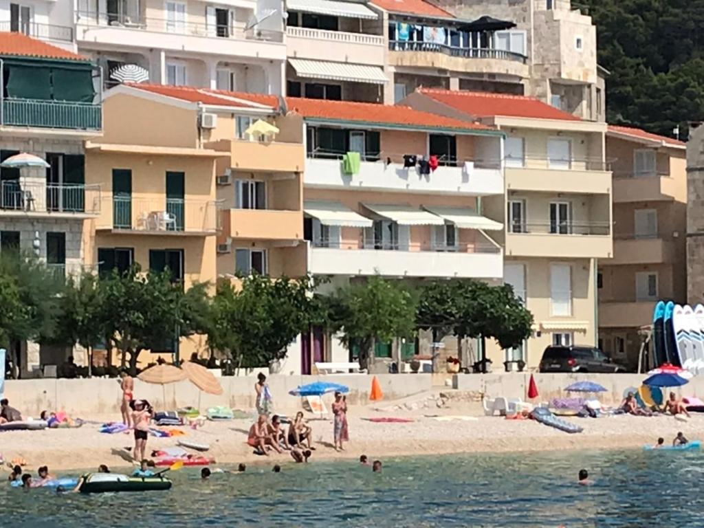 un groupe de personnes sur une plage avec des bâtiments dans l'établissement Apartmani Miranda, à Drašnice