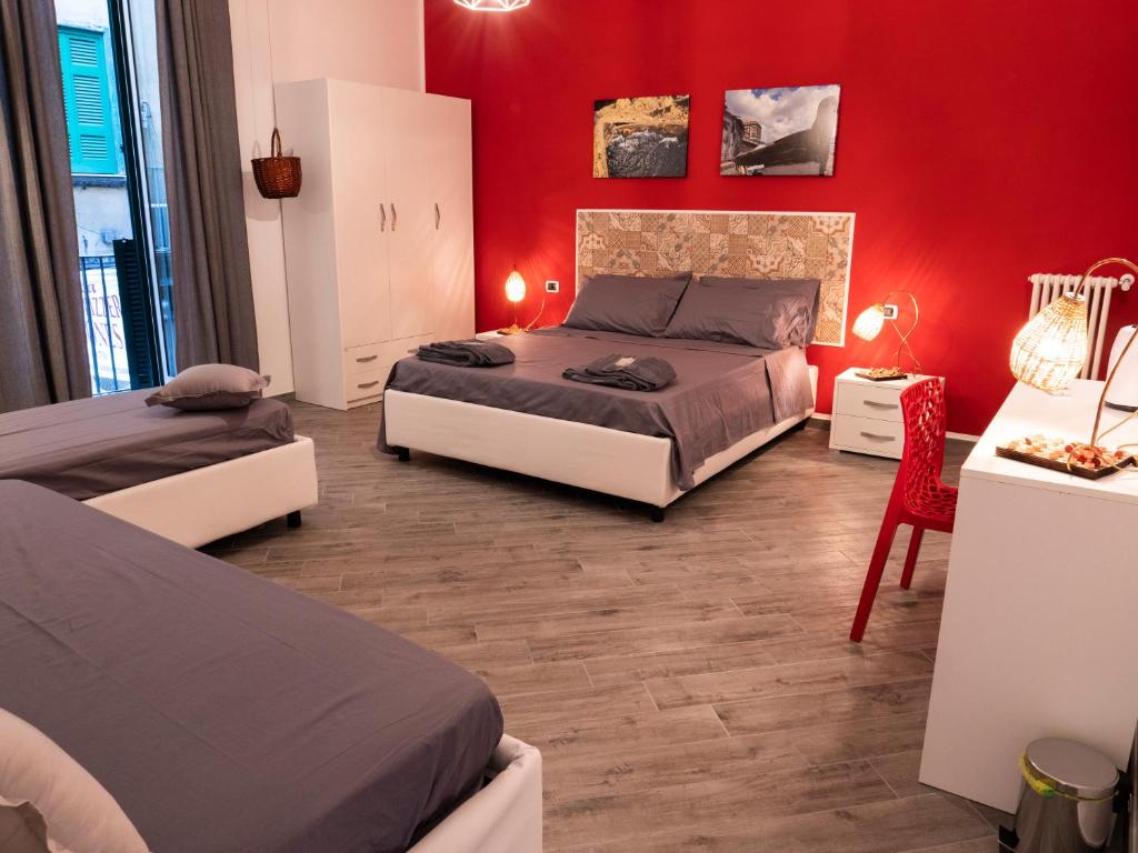 um quarto com 2 camas e uma parede vermelha em B&B Cosmoneapolitan em Nápoles